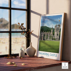 Framed Balmoral Castle travel poster on sunny windowsill with vases and beach view