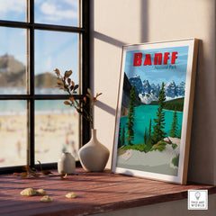 Framed Banff National Park travel poster on a windowsill with vases and beach view
