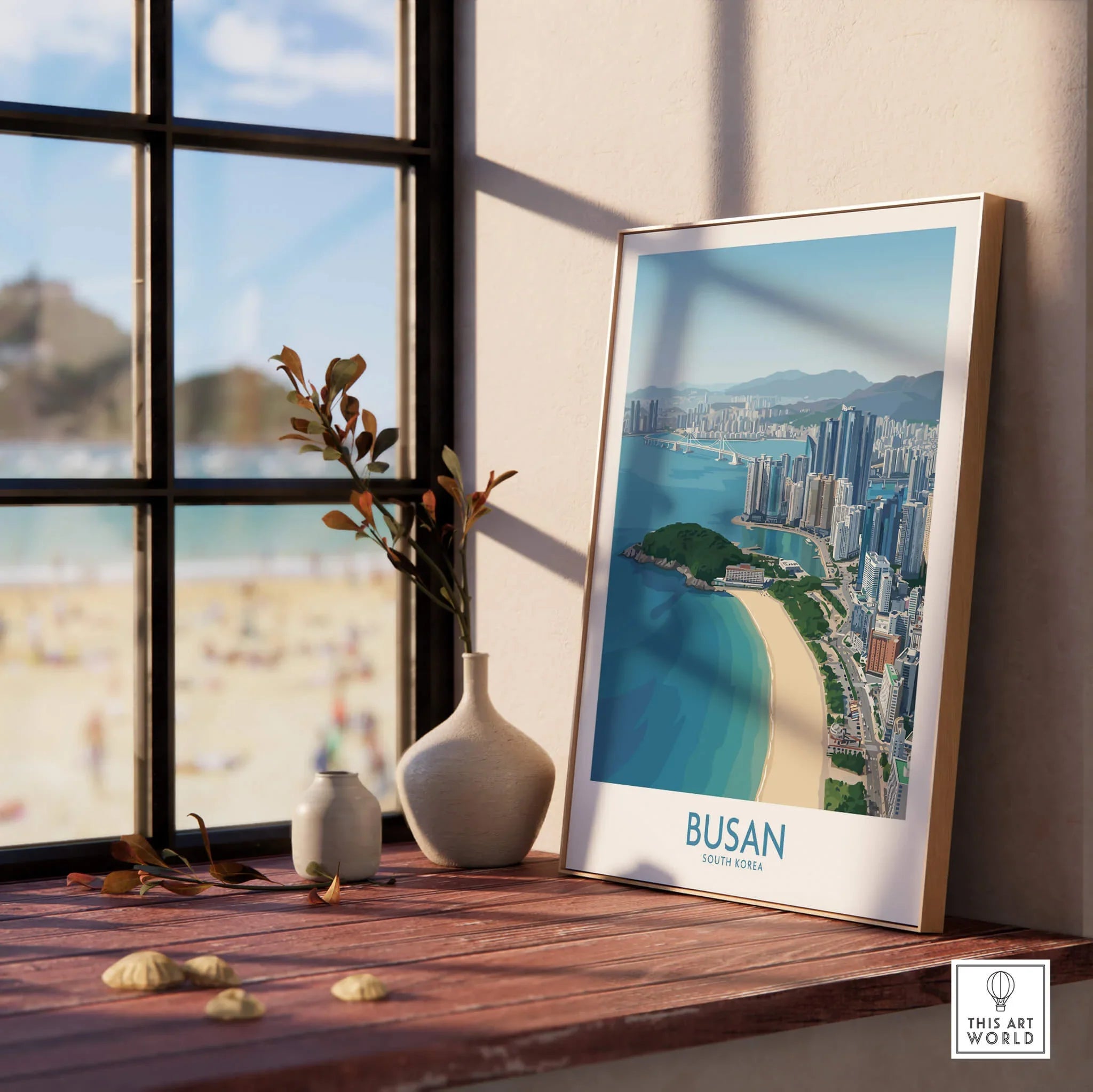 Framed Busan skyline travel poster on window sill with vases, beach view outside window