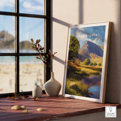 Framed Cadair Idris Wales travel poster on windowsill with vases and scenic beach view