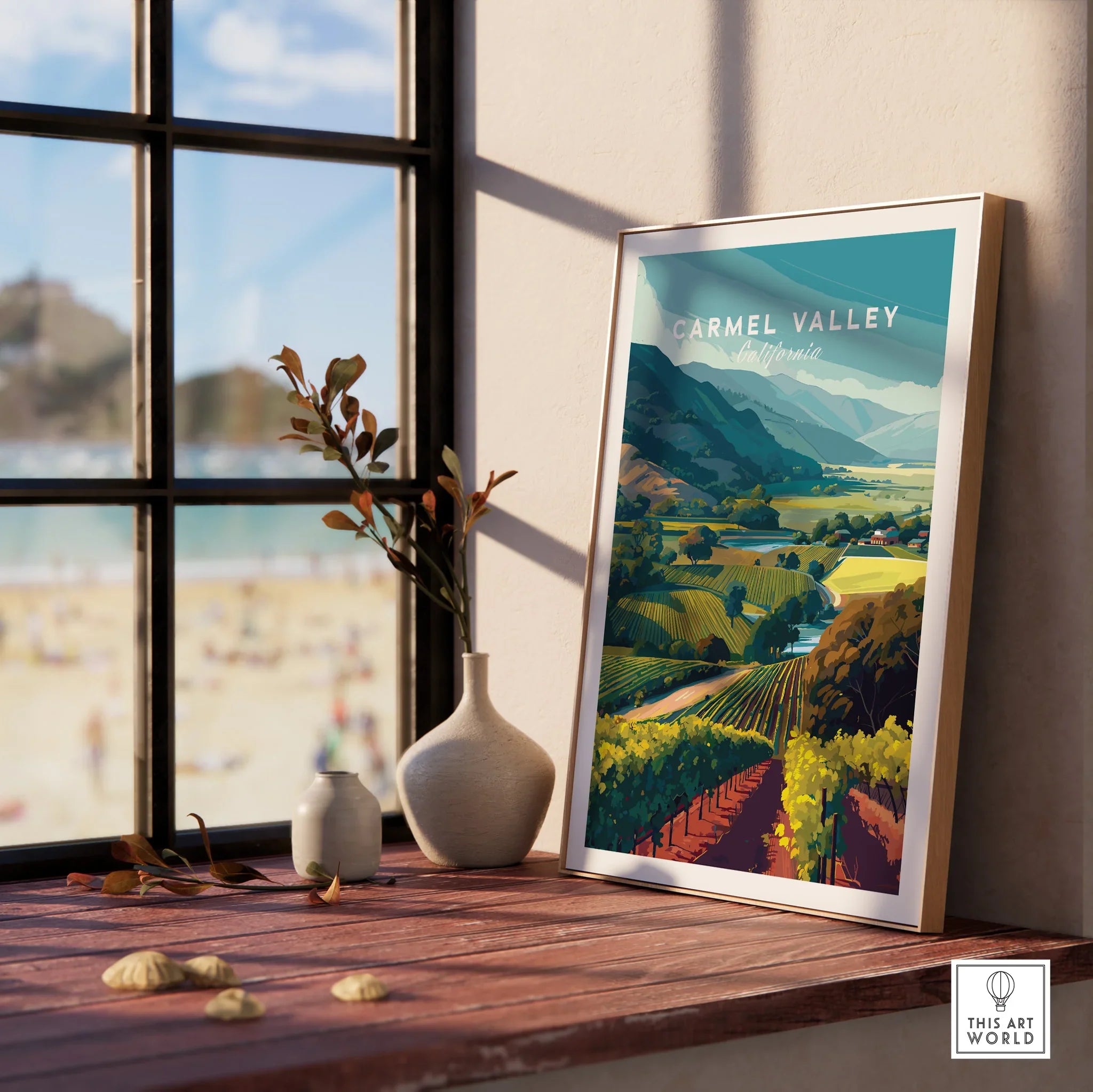 Framed Carmel Valley California art print on sunlit windowsill, with vases and scenic view.