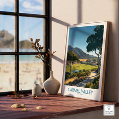 Framed Carmel Valley travel poster on a sunlit windowsill with beach view and ceramic vases.