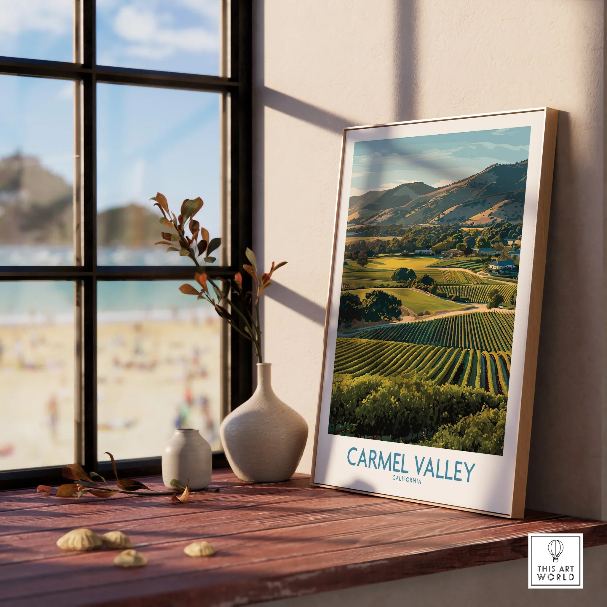Framed Carmel Valley travel poster with vineyard landscape on a sunny windowsill, next to vases.