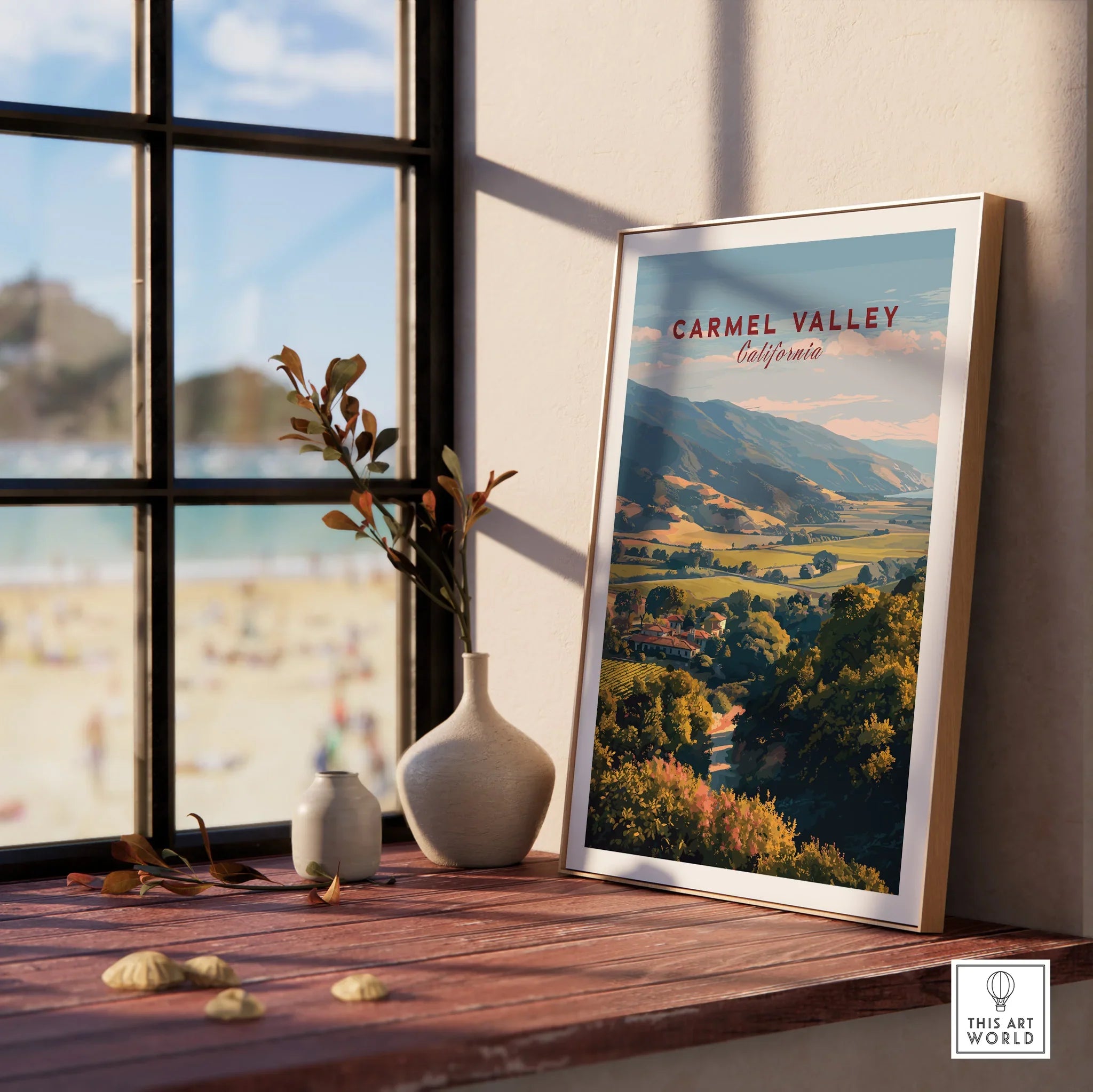 Framed Carmel Valley California travel poster on a wooden windowsill with vases and beach view
