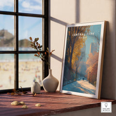 Framed Central Park print in natural wood frame on windowsill with vases, autumn cityscape art