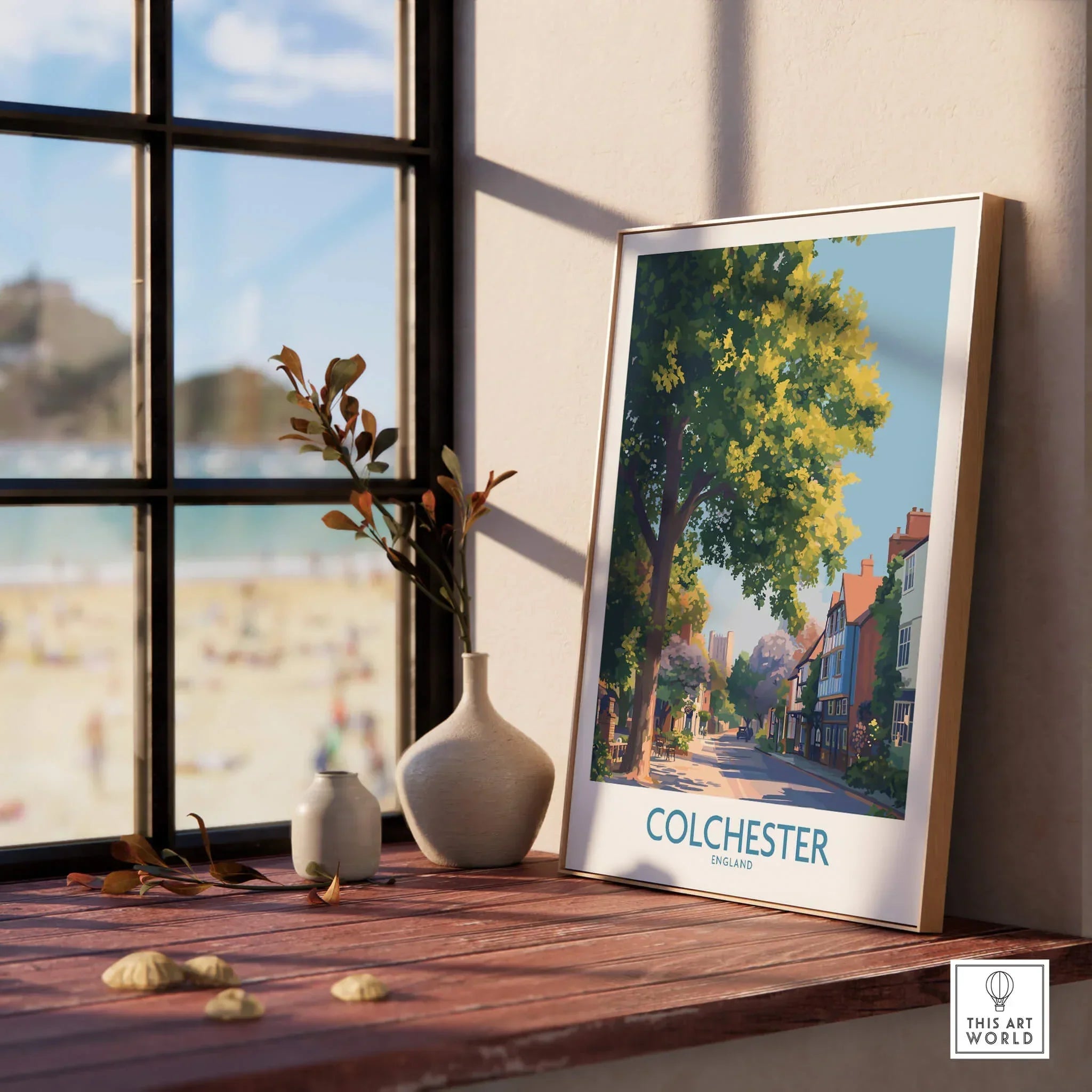 Framed Colchester travel poster with natural wood frame on a windowsill, beach view outside