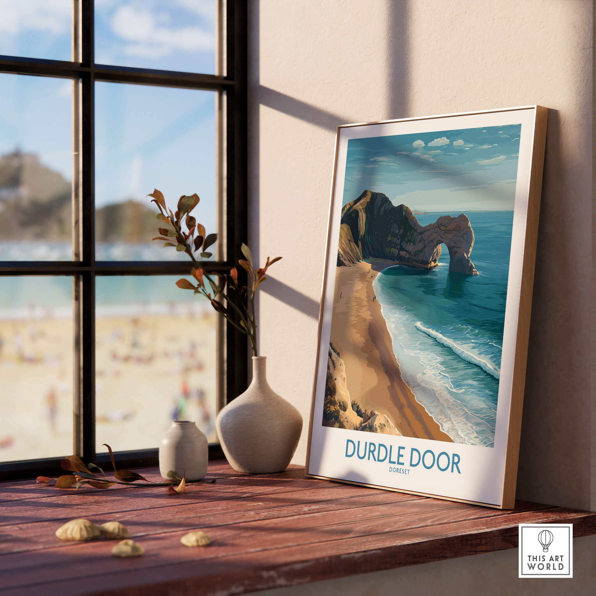 Durdle Door Art Print Dorset Wall Art displayed on a wooden table with a beach view in the background.