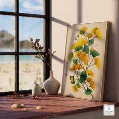 Framed botanical print with yellow and green leaves on a windowsill, beach view outside