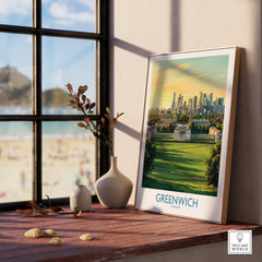 Framed Greenwich London travel art print on windowsill with sunlight and vases, city skyline view.