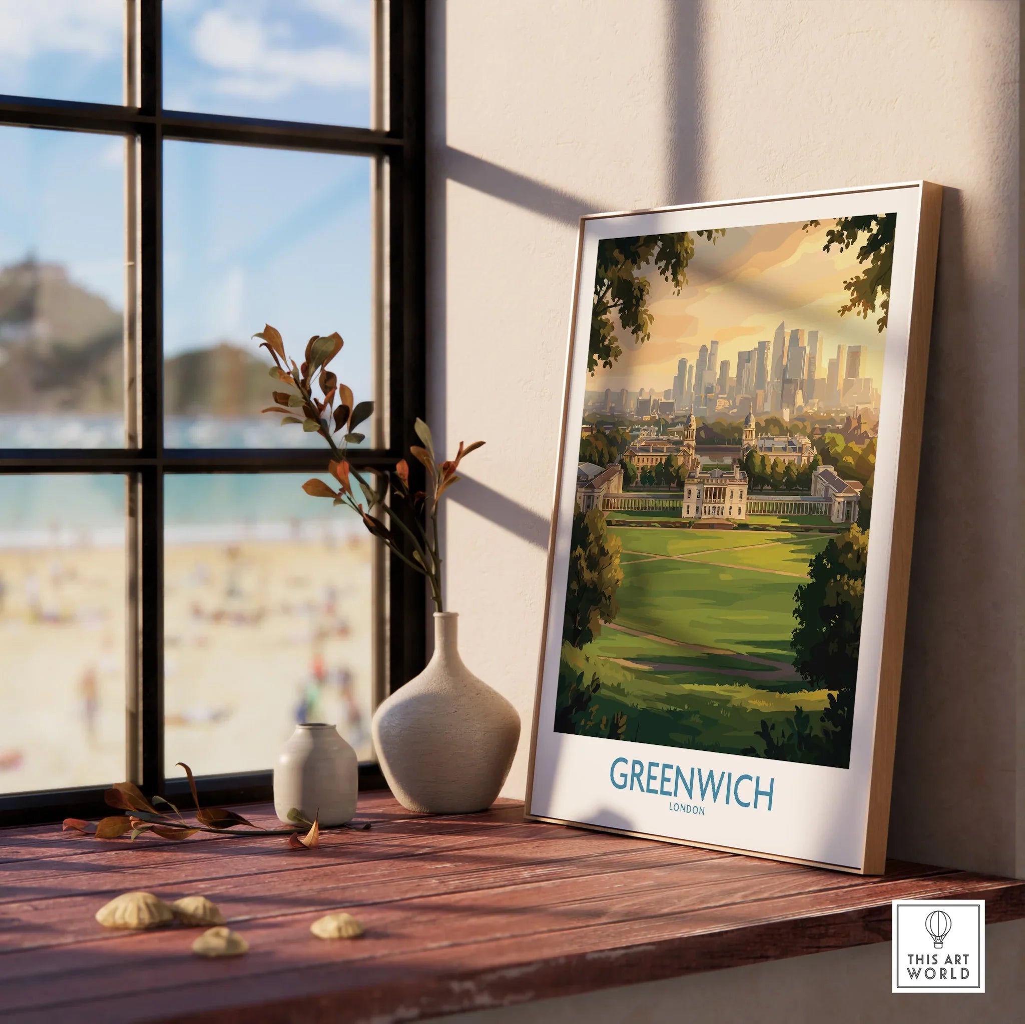 Framed Greenwich London cityscape print on a windowsill with natural wood frame, vases, and seaside view