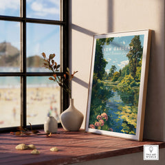 Framed Kew Gardens art print by a window with vases on a wooden ledge and beach view outside.