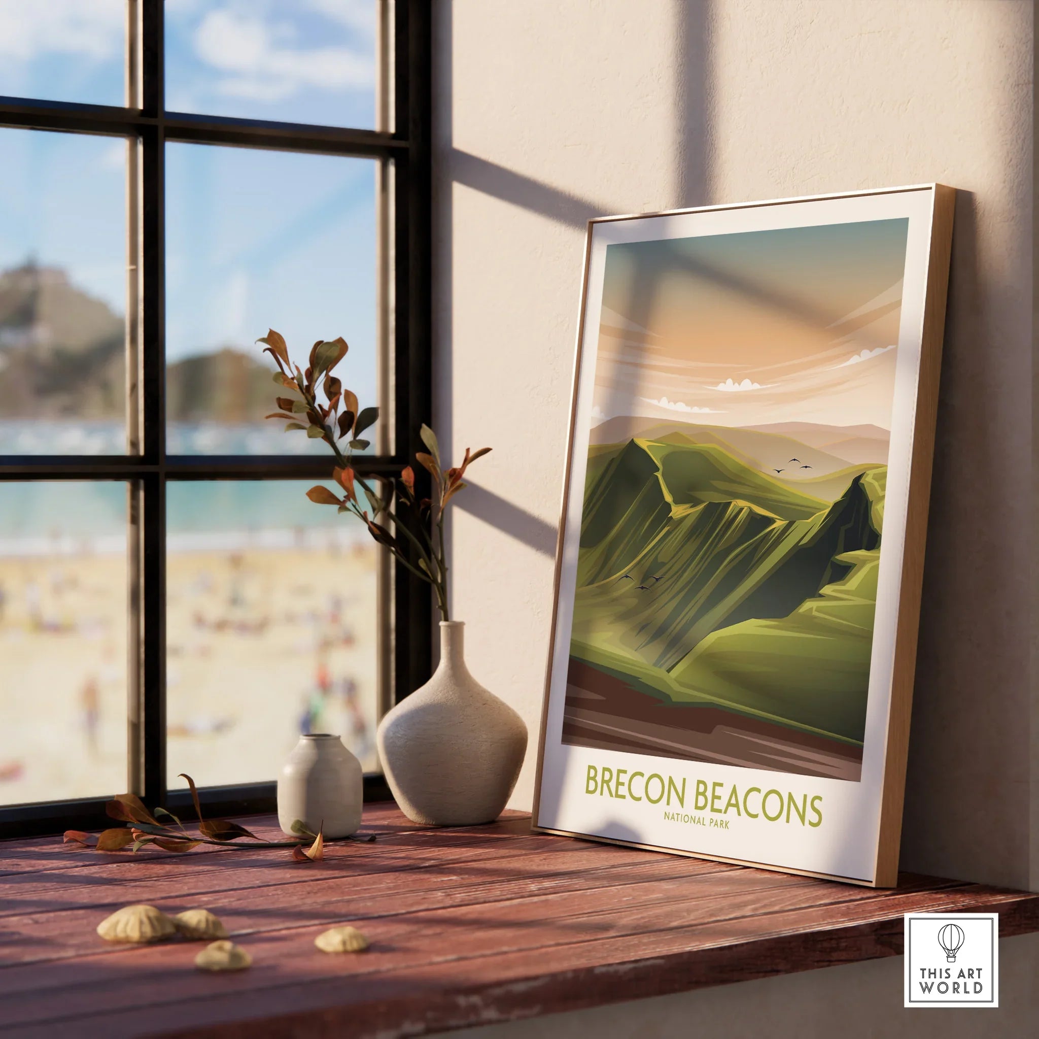 Framed Brecon Beacons National Park art print on windowsill with beach view and vases