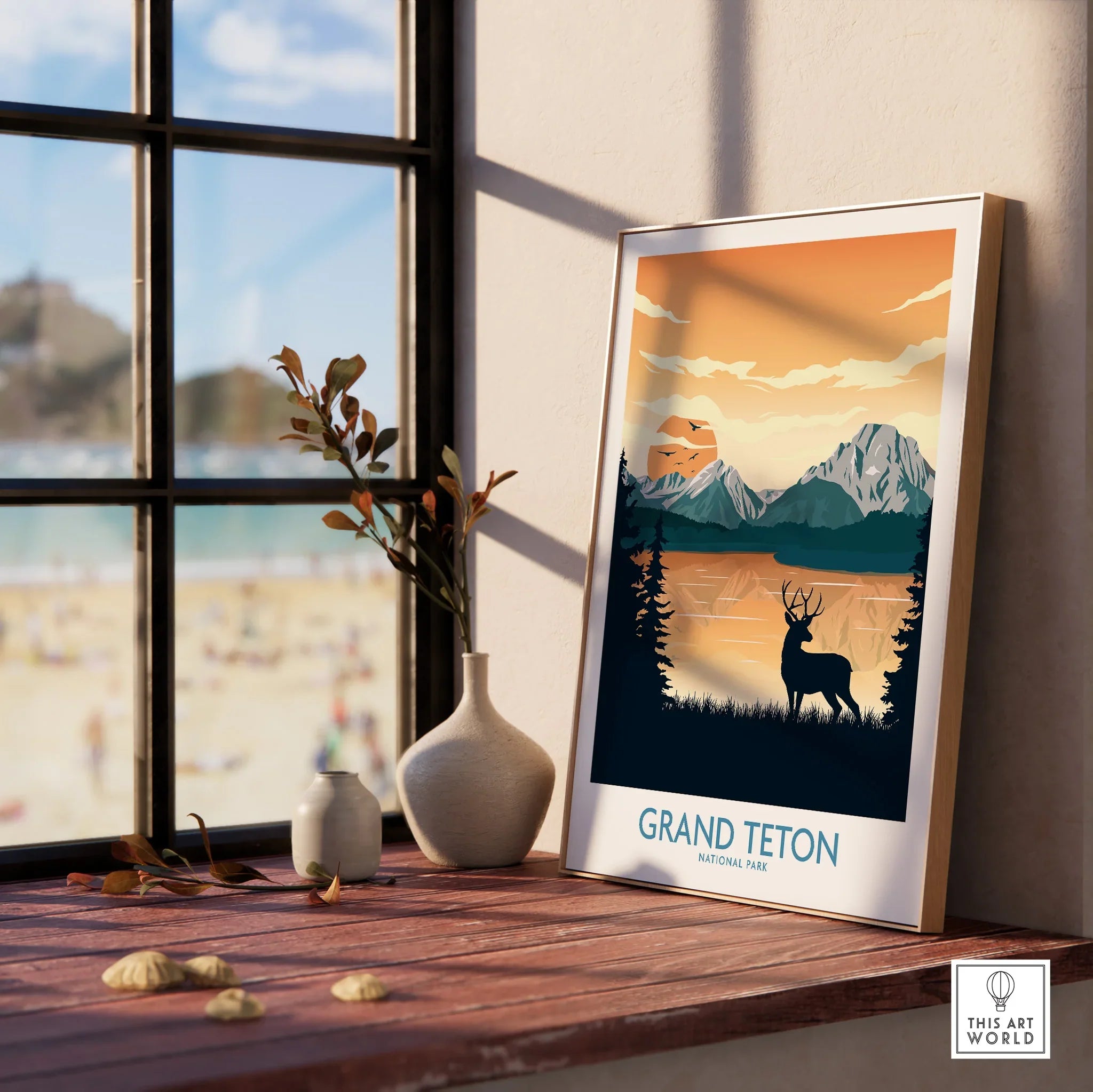 Framed Grand Teton National Park print with mountain, lake, and deer, on a window sill.