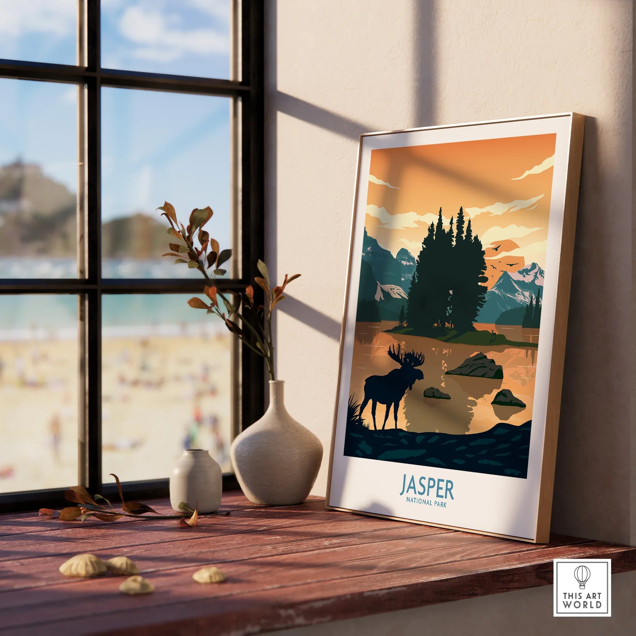 Framed Jasper National Park print with moose and mountain landscape on a sunny windowsill.