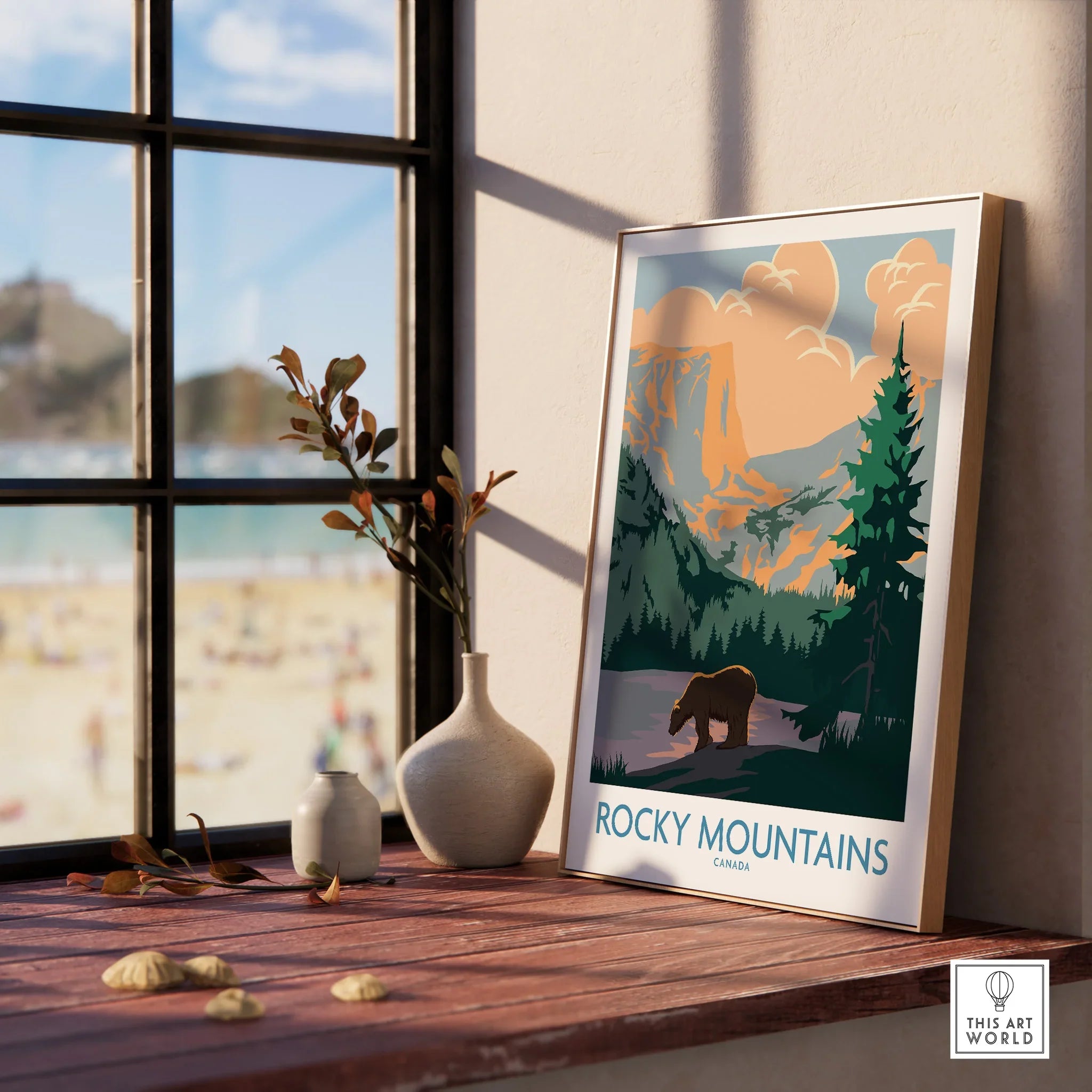 Framed Rocky Mountains Canada travel poster on windowsill with vases and scenic view outside.