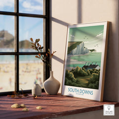 South Downs National Park framed print in natural wood frame on windowsill, beach view outside.