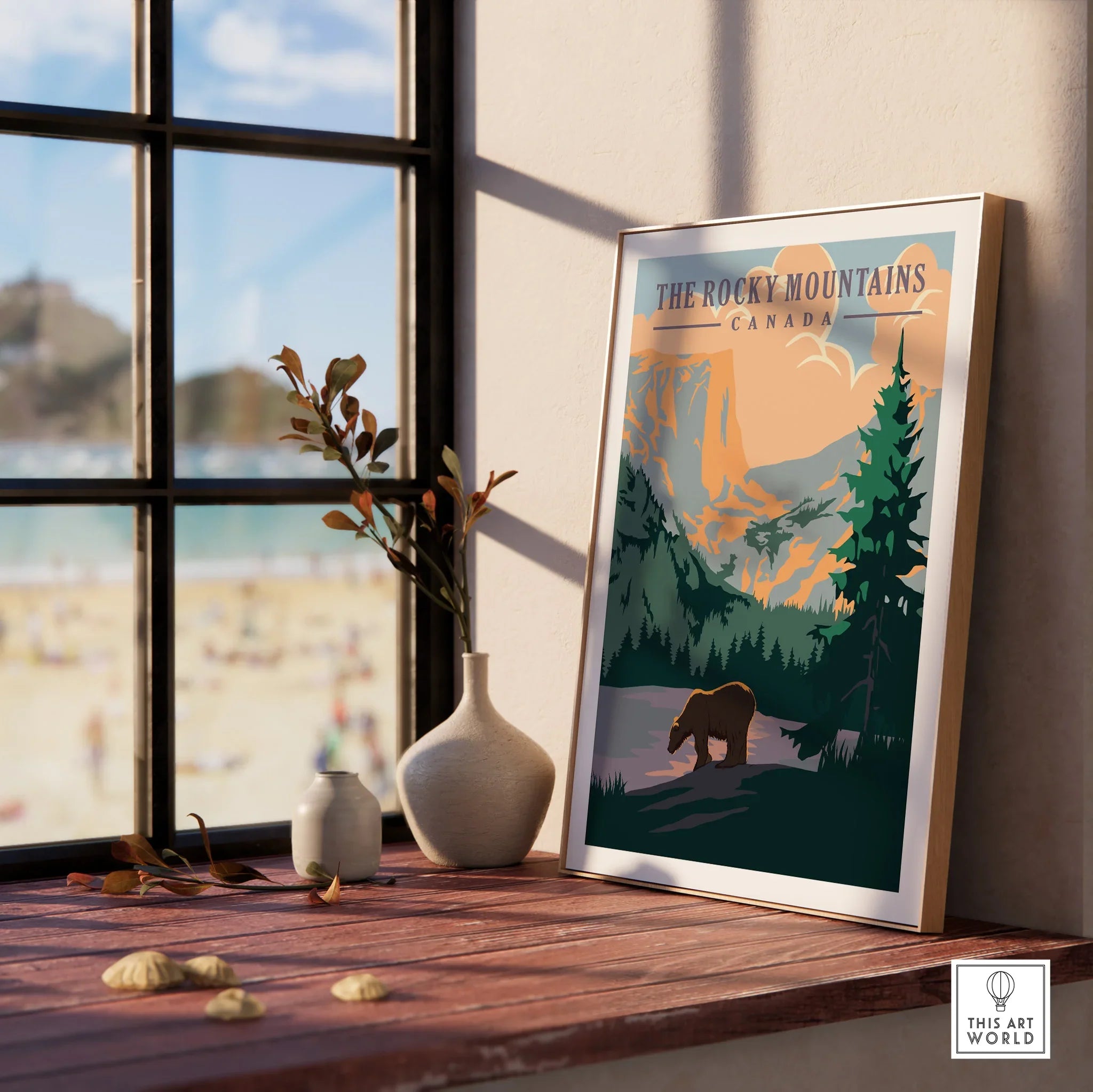 Framed Rocky Mountains Canada travel poster print on window sill with vases and beach view