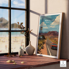 Framed Route 66 travel poster with desert landscape on a wooden windowsill, beach view outside.
