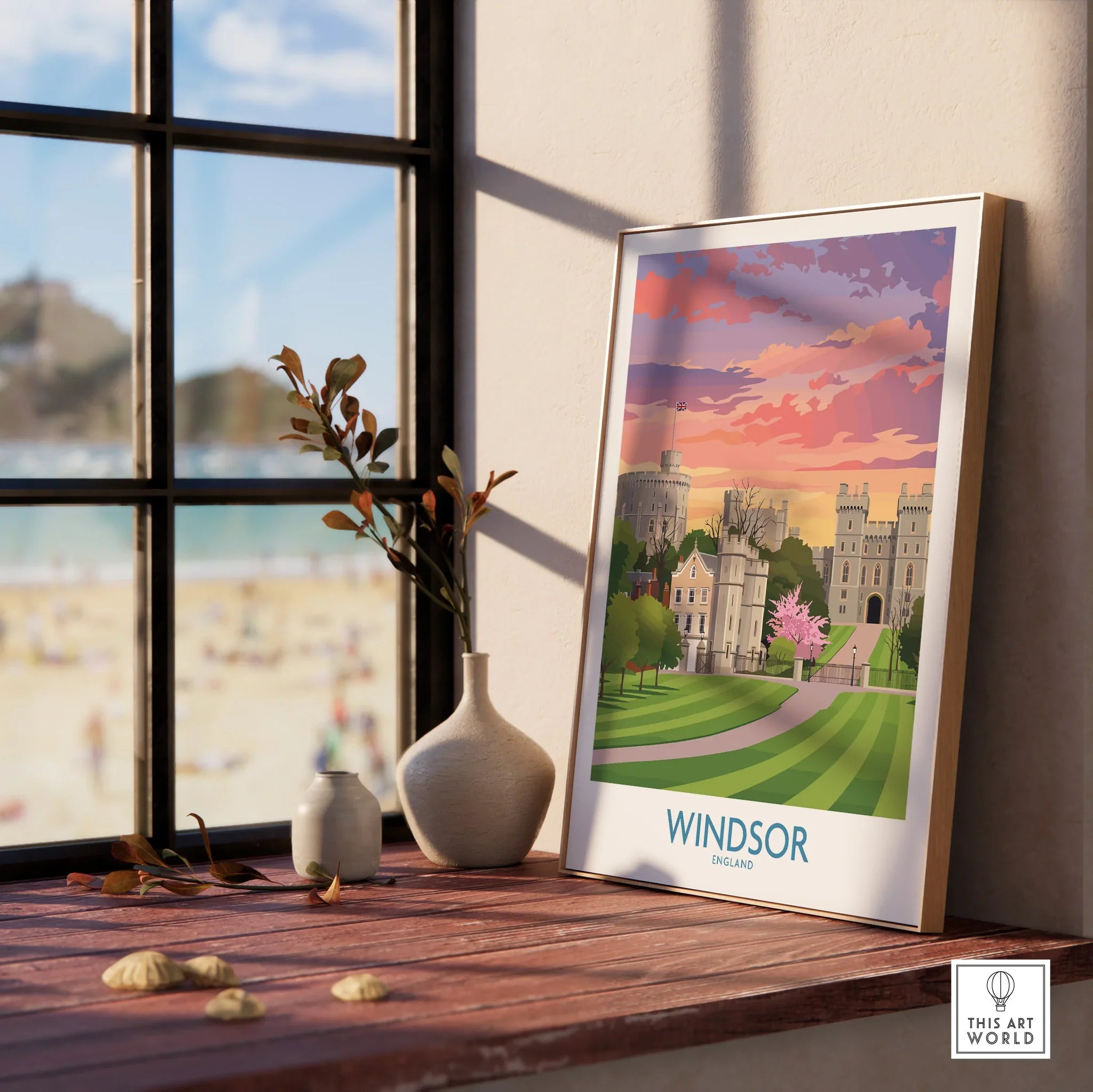Windsor England art print in natural wood frame beside vases on window sill, beach view outside.