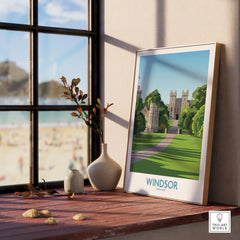 Framed Windsor travel poster with castle illustration on windowsill, beside vases, overlooking beach.