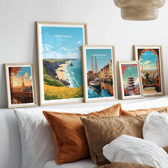 Cornwall Poster in a gallery wall set of five framed travel prints in natural wood frames above a bed