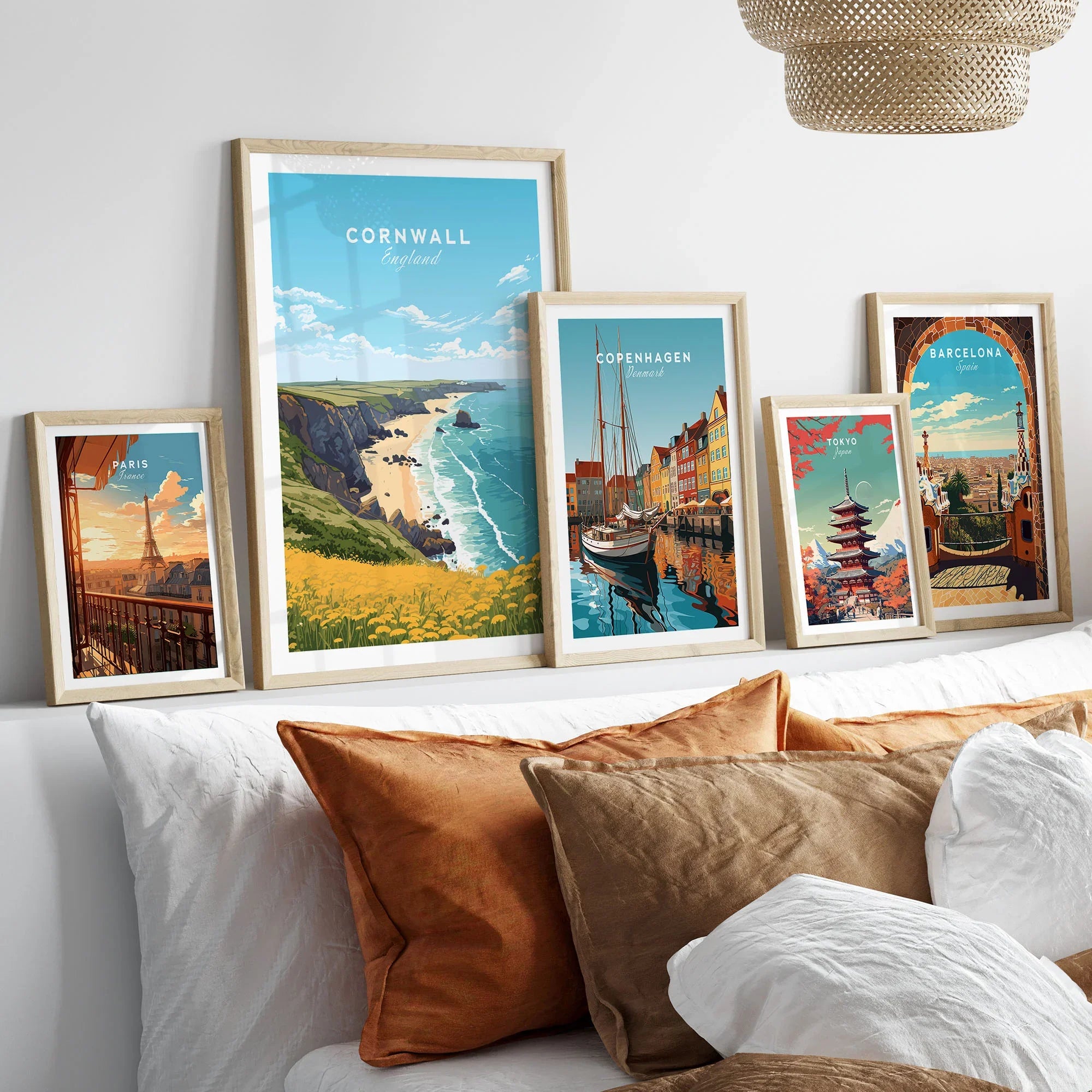Cornwall Poster in a gallery wall set of five framed travel prints in natural wood frames above a bed