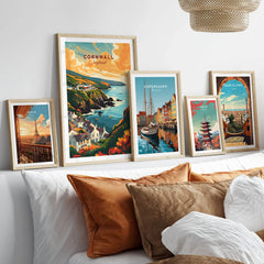 Cornwall Travel Print in a gallery wall set of five framed travel prints in natural wood frames above a bed