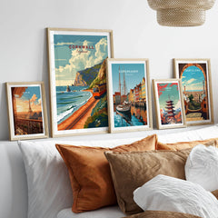 Cornwall Coast Travel Print in a gallery wall set of five framed travel prints in natural wood frames above a bed
