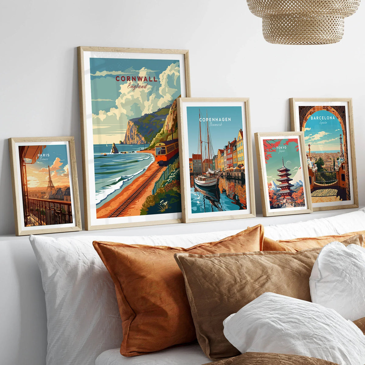 Cornwall Coast Travel Print in a gallery wall set of five framed travel prints in natural wood frames above a bed