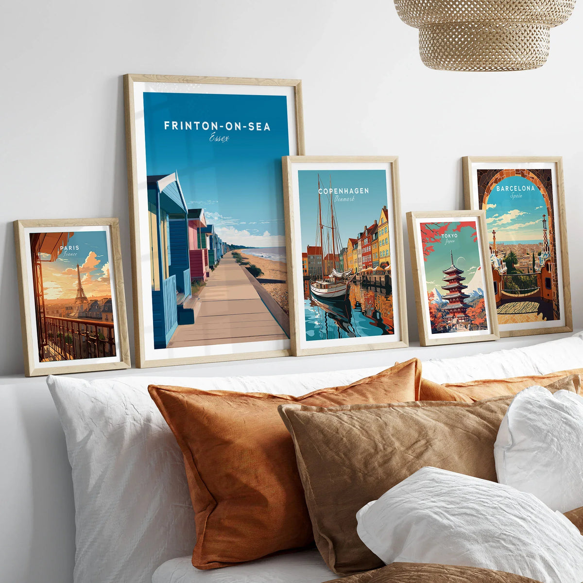 Frinton-on-Sea Travel Poster – Essex Coastline Beach Huts & Prom Art in a gallery wall set of five framed travel prints in natural wood frames above a bed