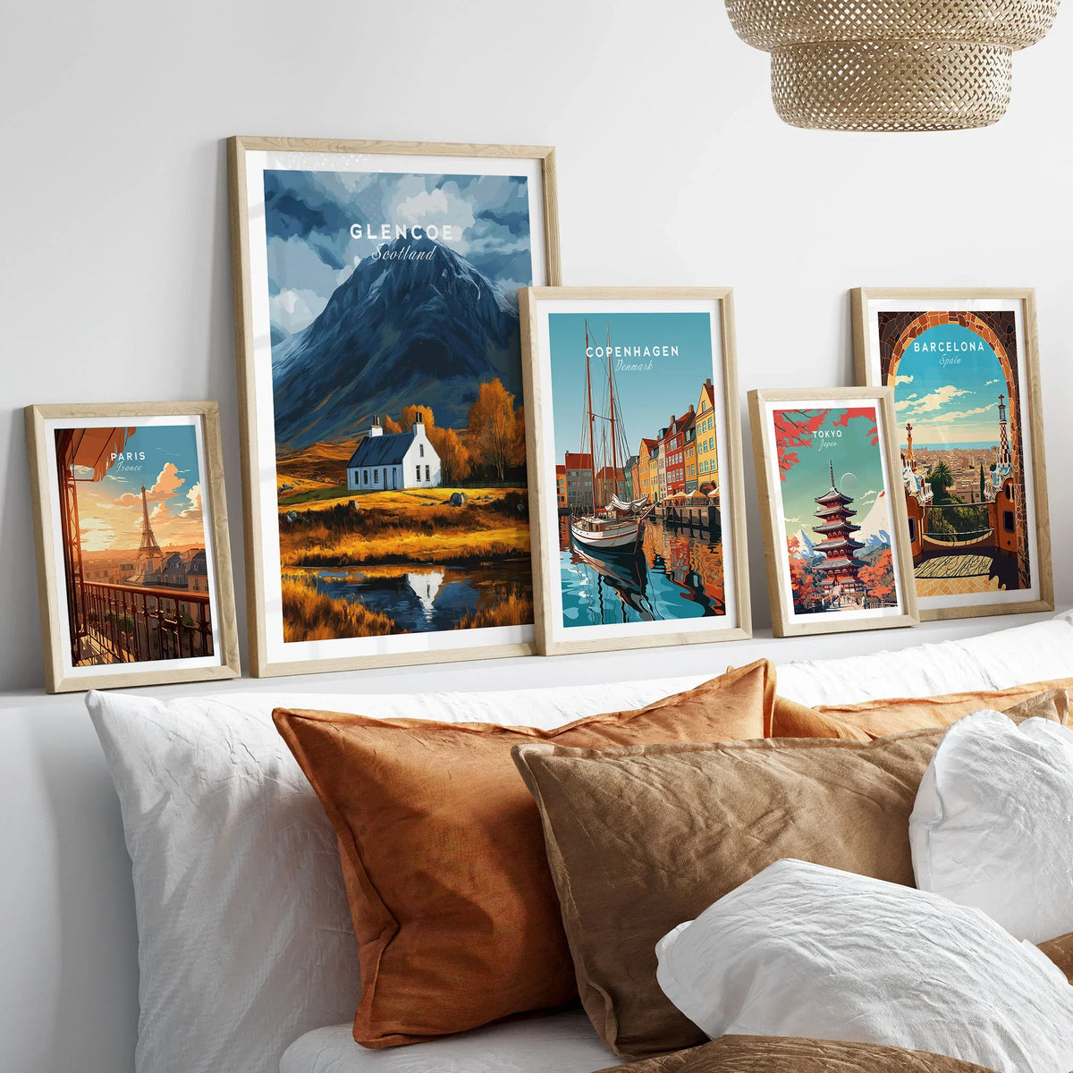 Glencoe Scotland Poster in a gallery wall set of five framed travel prints in natural wood frames above a bed