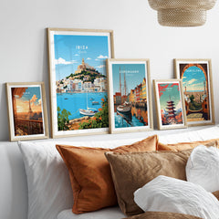 Ibiza Print in a gallery wall set of five framed travel prints in natural wood frames above a bed