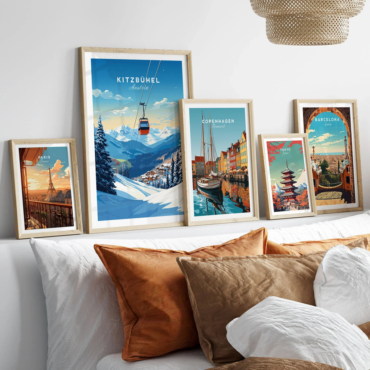 Kitzbuhel Art Print in a gallery wall set of five framed travel prints in natural wood frames above a bed
