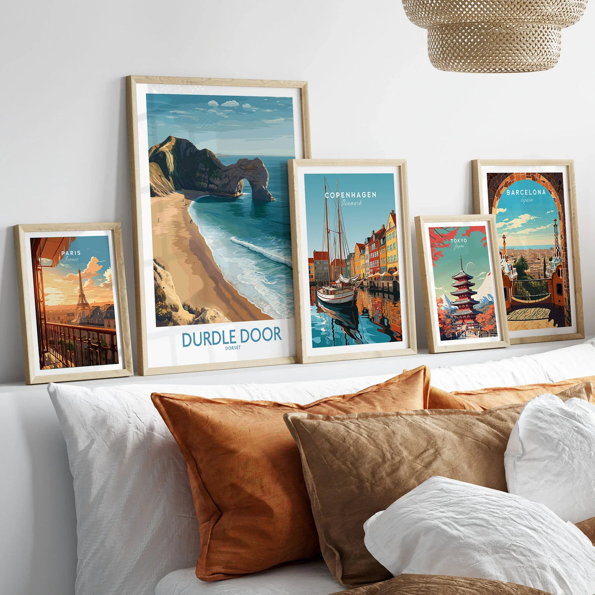 Durdle Door Art Print Dorset Wall Art in a gallery wall set of five framed travel prints in natural wood frames above a bed