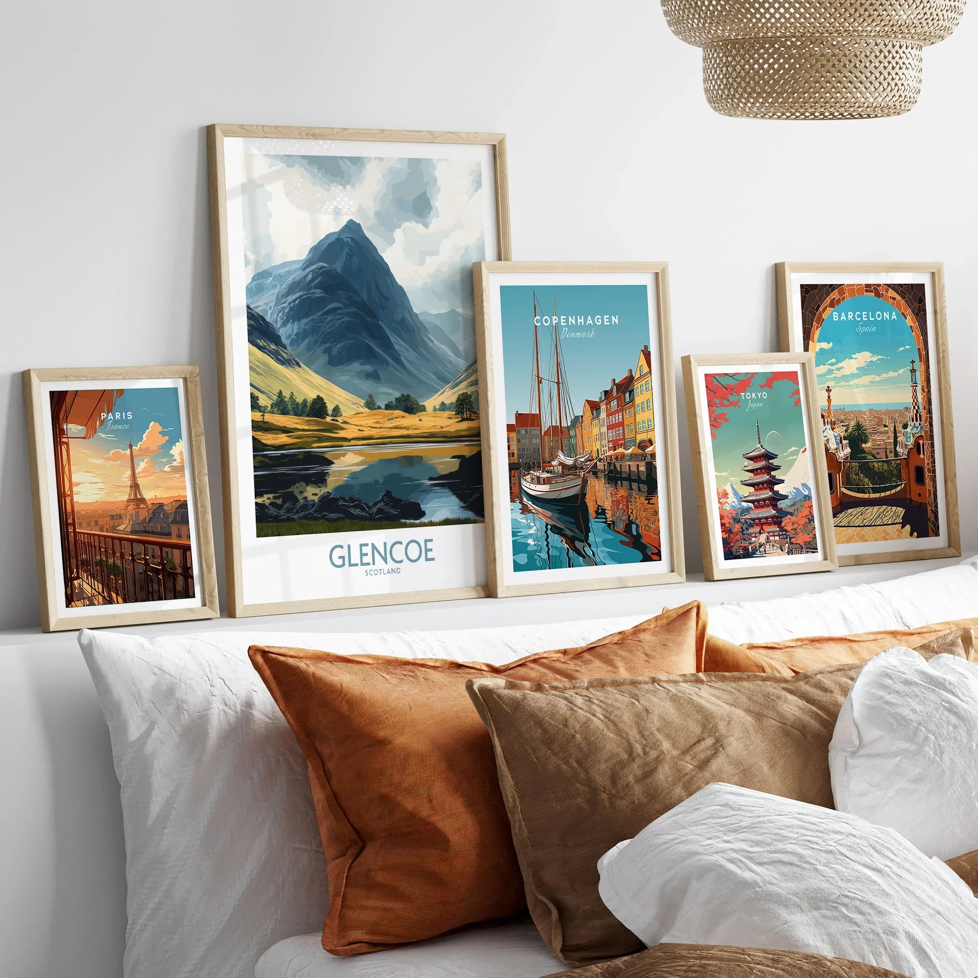 Glencoe Travel Poster in a gallery wall set of five framed travel prints in natural wood frames above a bed