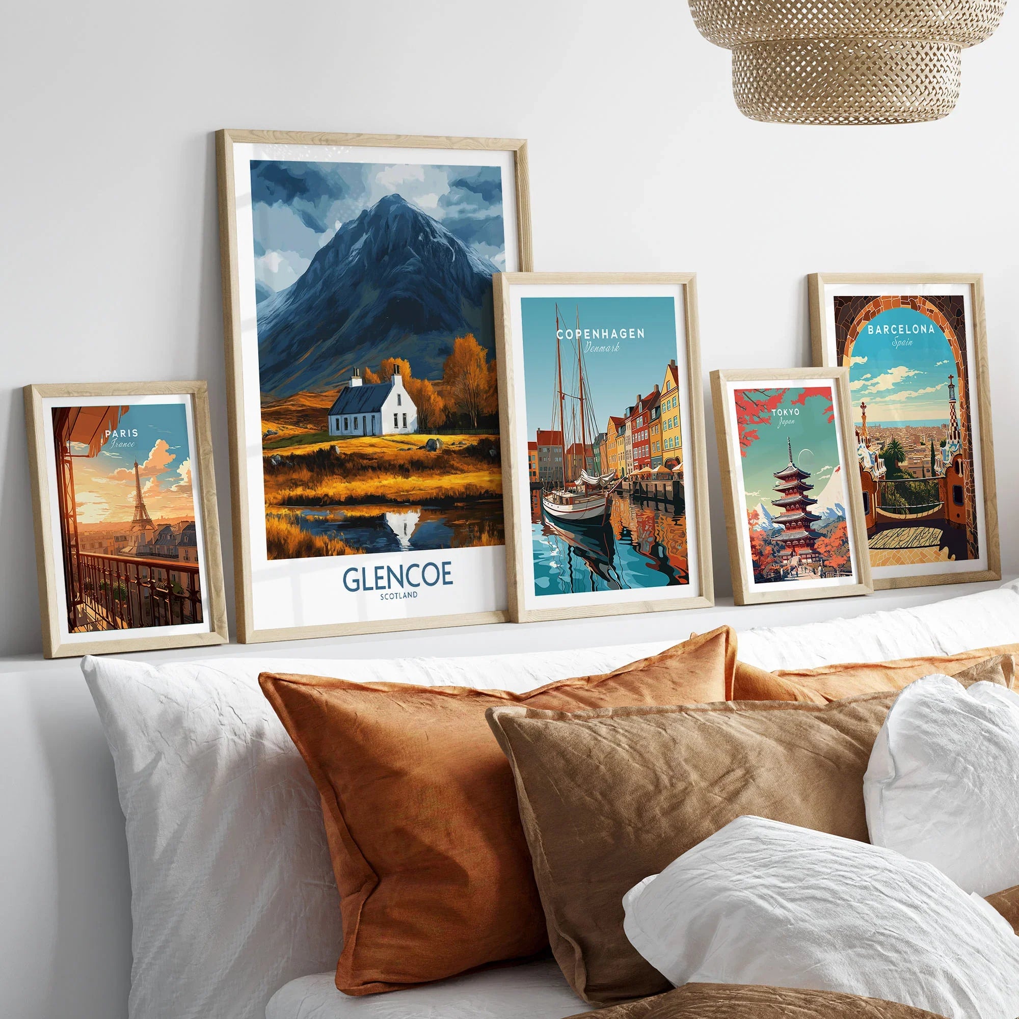 Glencoe Scotland Print in a gallery wall set of five framed travel prints in natural wood frames above a bed
