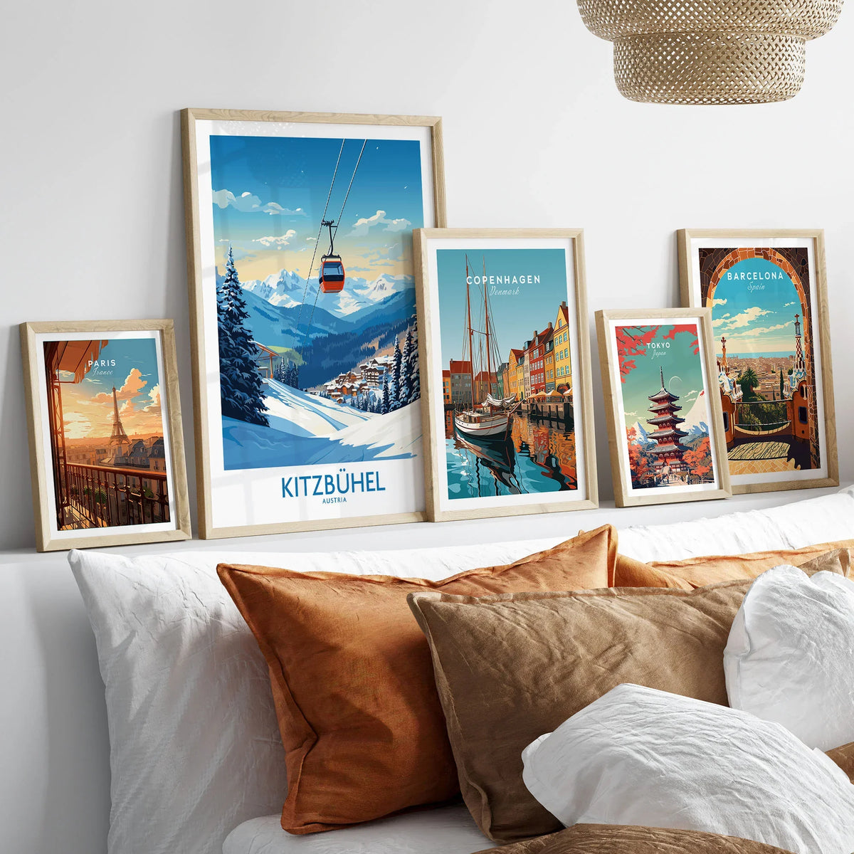 Kitzbuhel Wall Art Print in a gallery wall set of five framed travel prints in natural wood frames above a bed