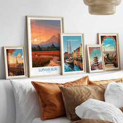 Suphan Buri Thailand Temple Sunset Wall Art — a lotus-covered lake and temple spire at sunset beneath a mountain peak, shown as set five framed artprints above bed natural wood frames