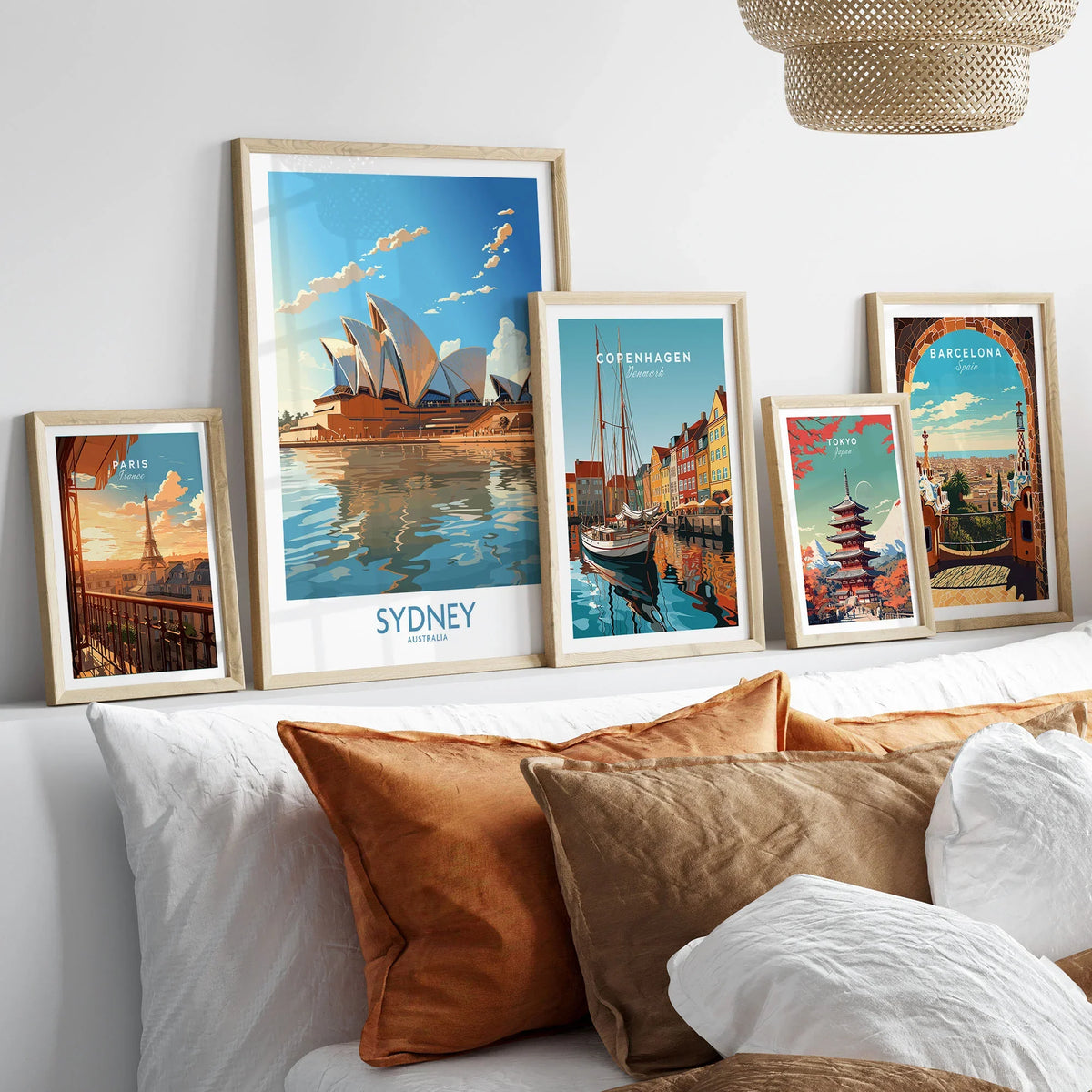 Sydney Print in a gallery wall set of five framed travel prints in natural wood frames above a bed