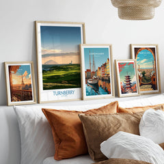 Turnberry Scotland Ayrshire Dusk Wall Art — Ailsa Craig and the white lighthouse across rolling coastal turf at dusk, shown as set five framed artprints above bed natural wood frames