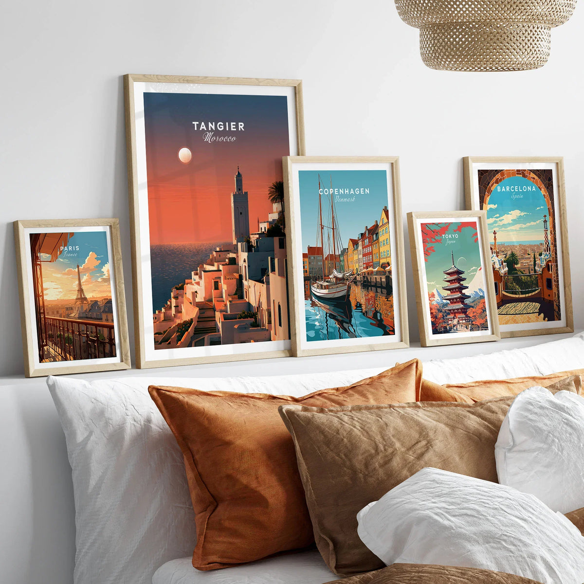 Tangier Morocco Golden Hour Travel Poster — a whitewashed hillside town and minaret glowing above the sea at sunset, shown as set five framed artprints above bed natural wood frames