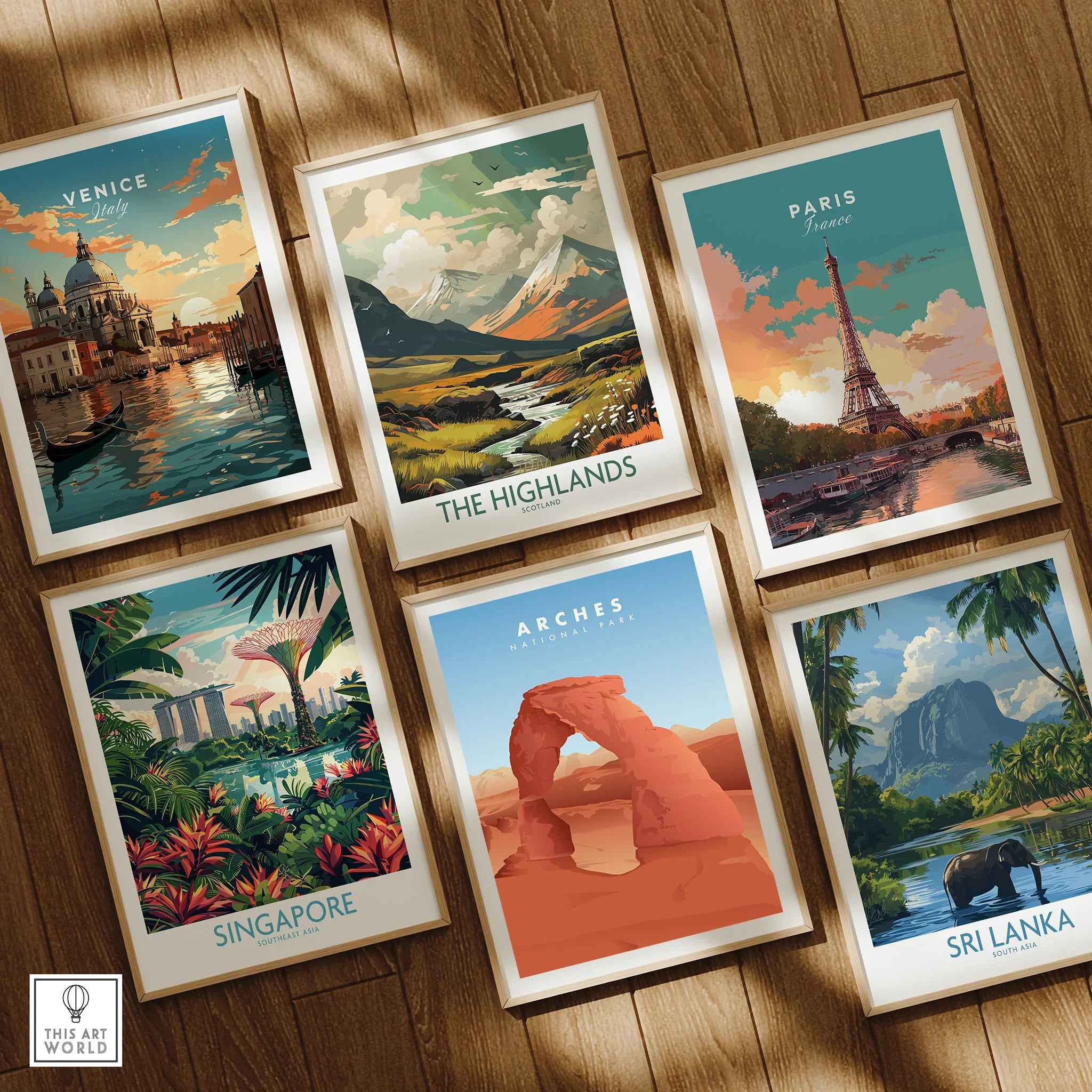 Six framed travel art prints on wooden floor featuring Venice, Paris, Highlands, Singapore, Arches National Park, and Sri Lanka.