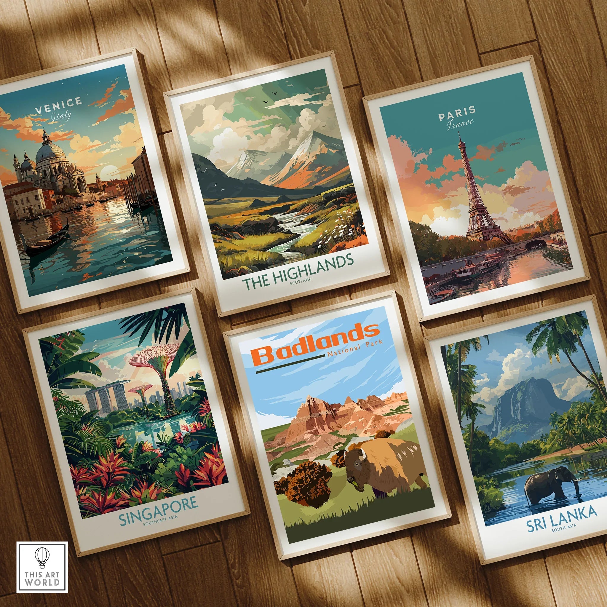 Six framed travel and national park art prints on wooden floor featuring Venice, Paris, Singapore, Badlands, the Highlands, and Sri Lanka.