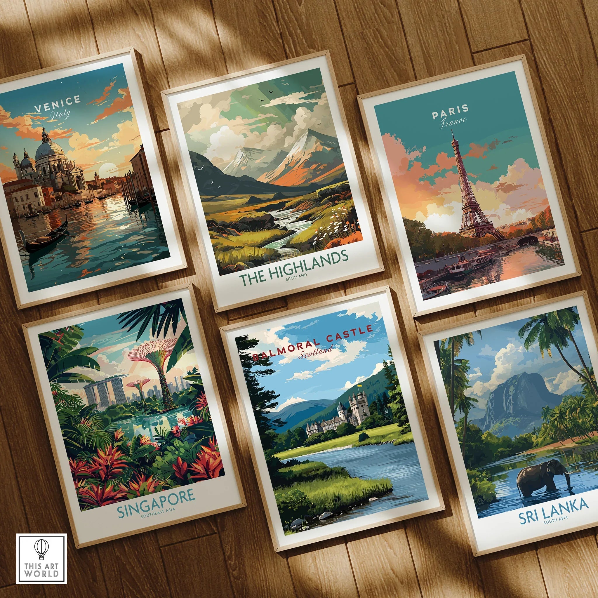 Set of six framed travel art prints on wooden floor, featuring Venice, Paris, The Highlands, Singapore, Balmoral Castle, and Sri Lanka landscapes.