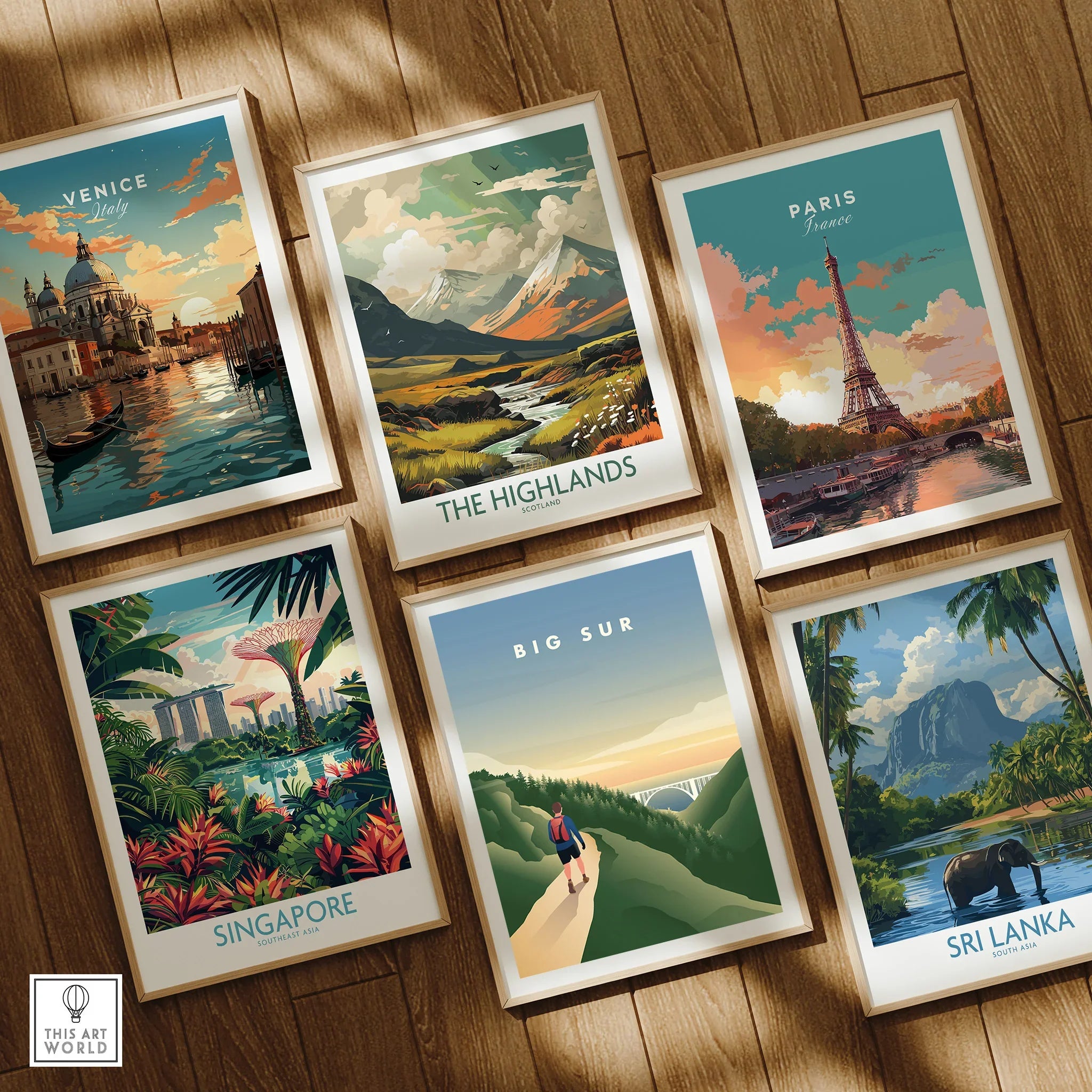 Six framed travel posters featuring Venice, the Highlands, Paris, Singapore, Big Sur, and Sri Lanka, displayed on a wooden floor.