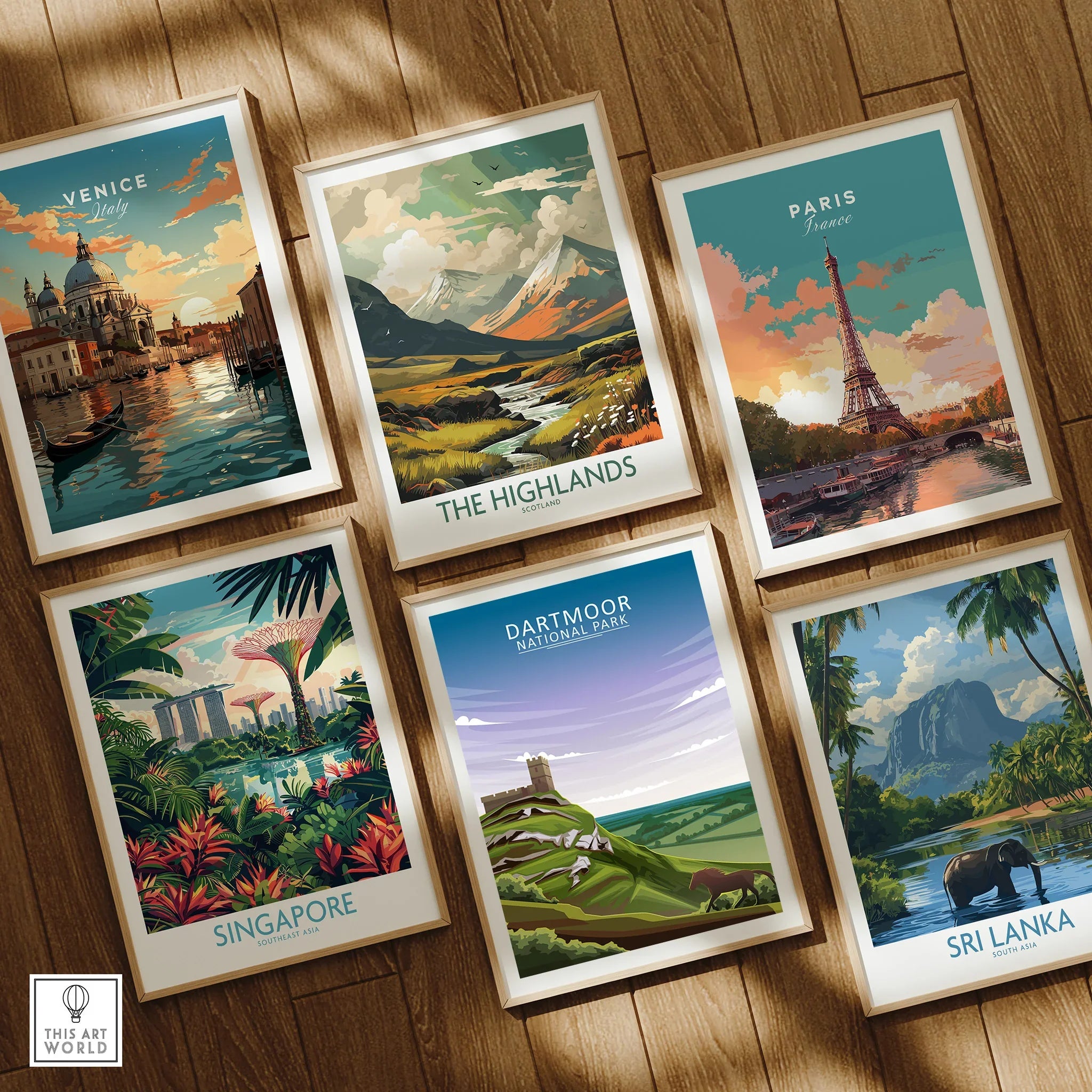 Set of six framed travel poster art prints featuring Venice, The Highlands, Paris, Singapore, Dartmoor National Park, and Sri Lanka on a wooden floor.