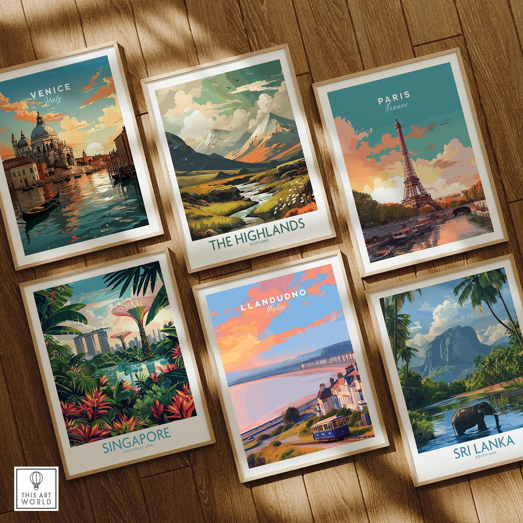 Set of six framed travel posters featuring Venice, Paris, Singapore, Scotland Highlands, Llandudno, and Sri Lanka, arranged on a wooden floor.
