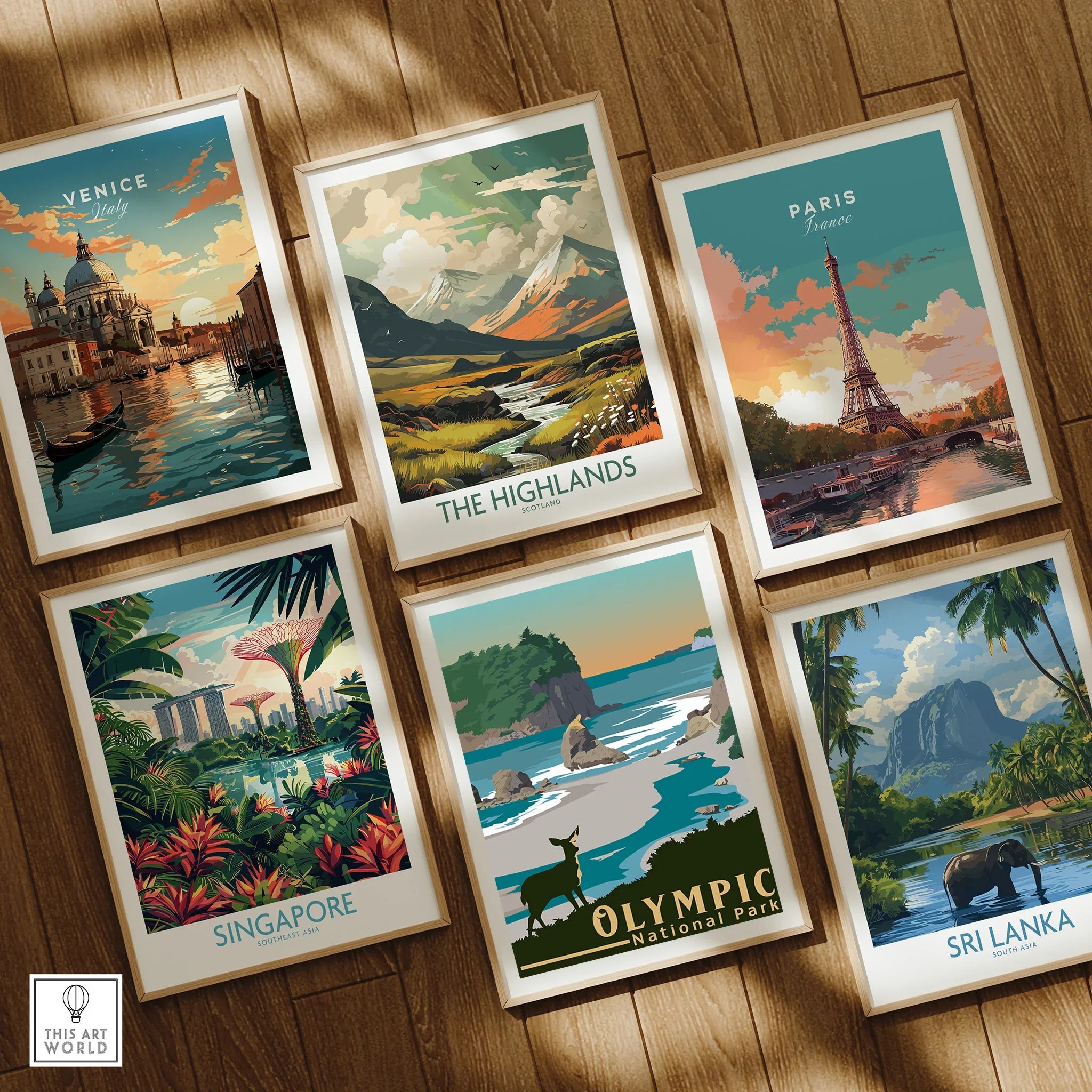 Set of six framed travel posters featuring Venice, the Highlands, Paris, Singapore, Olympic National Park, and Sri Lanka on a wooden floor.