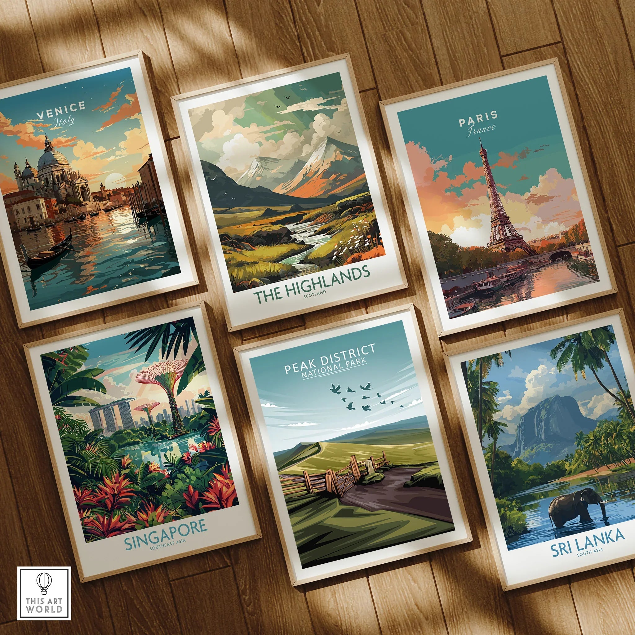 Set of six framed travel posters featuring Venice, Paris, Singapore, The Highlands, Peak District, and Sri Lanka, arranged on a wooden floor.