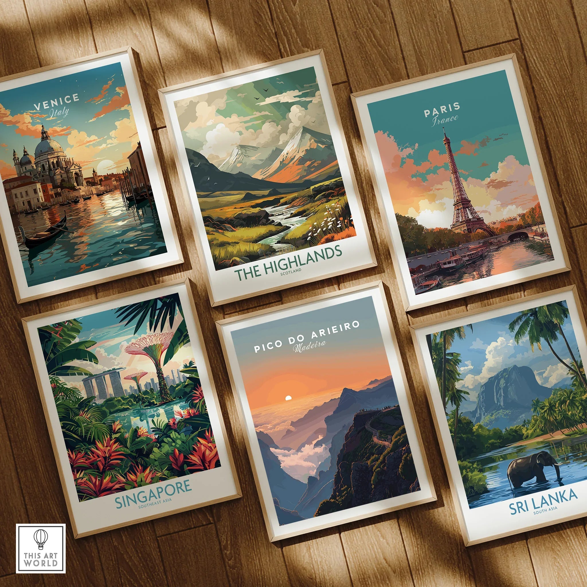 Set of six framed travel posters featuring Venice, Paris, Scottish Highlands, Singapore, Pico do Arieiro, and Sri Lanka on a wooden floor.